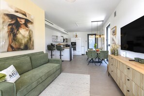 Ein modernes Wohnzimmer mit einem grünen Sofa, einem Essbereich und einer Küche.