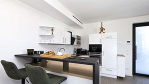 Eine moderne Küche mit Bar, weißen Schränken und einer Kaffeemaschine.