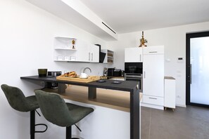 Eine moderne Küche mit Bar, weißen Schränken und einer Kaffeemaschine.
