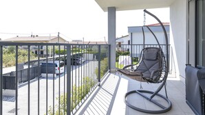 Ein Balkon mit einer Hängematte, Blick auf einen Parkplatz und ein Gebäude im Hintergrund.