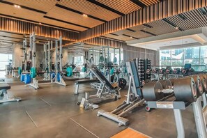 Une salle de sport équipée de divers appareils d’exercice, dotée de grandes fenêtres et d’un design moderne au niveau du plafond.
