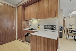 Eine moderne Küche mit Holzschränken, einer Mikrowelle und einem Einbauofen.