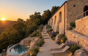 Ein Gebäude aus Stein mit Pool und Liegestühlen.