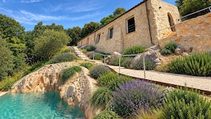 A stone building with a pool, surrounded by lush greenery and a clear sky. - Stunning home in Roccantica (Roccantica)