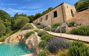 A stone building with a pool, surrounded by lush greenery and a clear sky. - Stunning home in Roccantica (Roccantica)