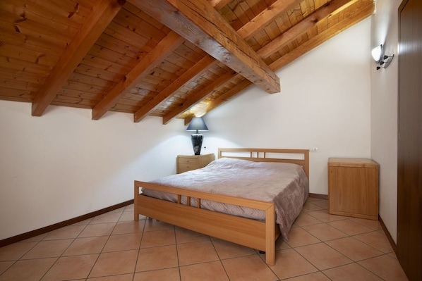 A bedroom with a wooden bed, a nightstand, a lamp, and a wardrobe.