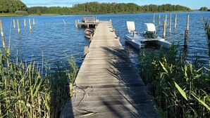 Eine hölzerne Pier, die sich in einen ruhigen See erstreckt, mit am Ende vertäuten Booten.
