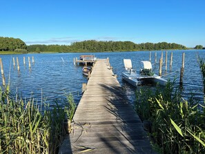 Eine hölzerne Pier, die sich in einen ruhigen See erstreckt, mit am Ende vertäuten Booten.