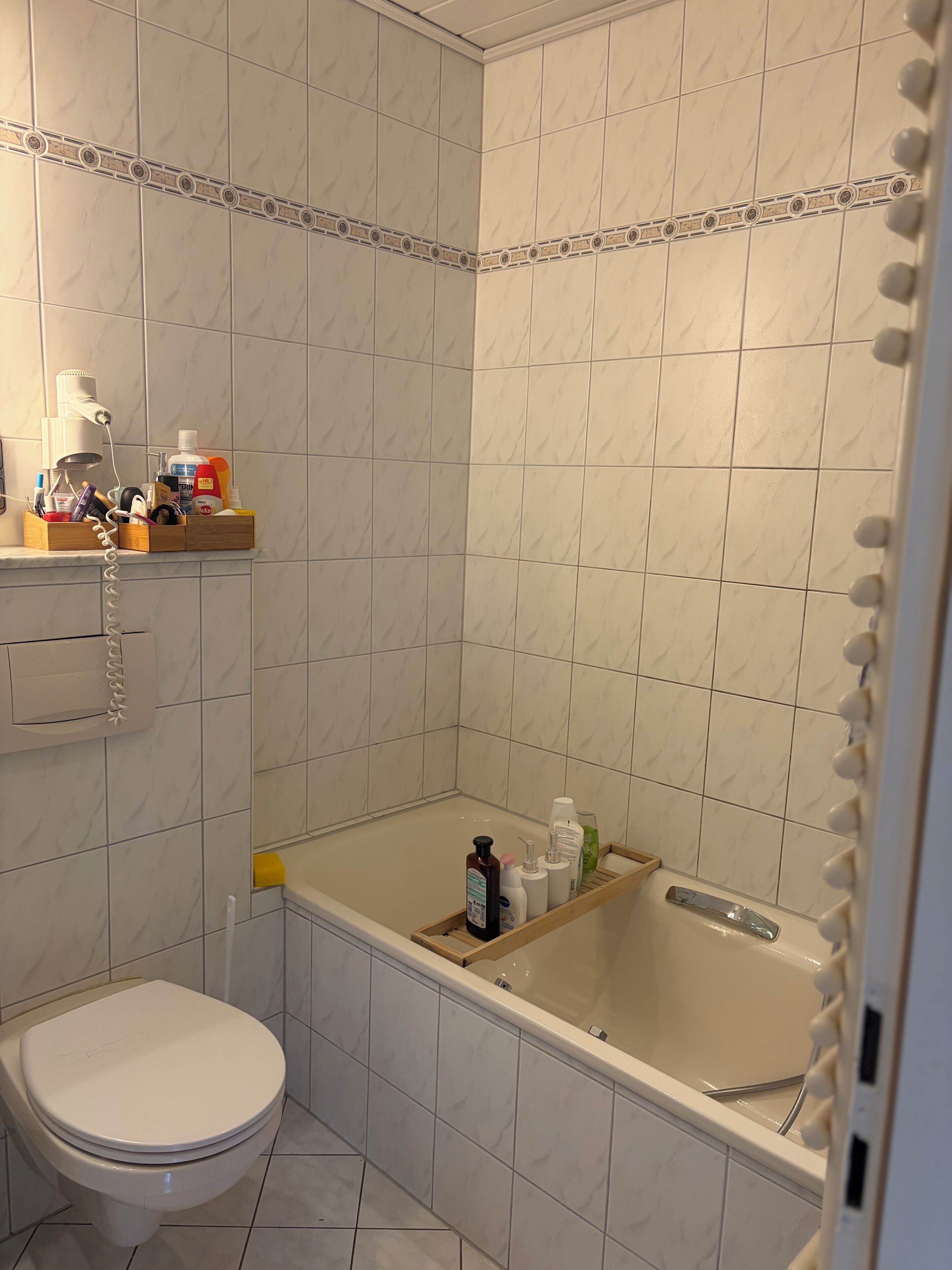 A bathroom with a toilet, a shower area, and a vanity with toiletries.