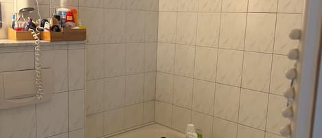 A bathroom with a toilet, a shower area, and a vanity with toiletries.