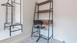 A room with a metal shelving unit against a wall, a black chair, and a window. - Modern Flat In Jewellery Quarter, Free Parking (Birmingham)