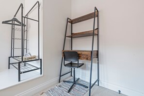 Ein Zimmer mit einem Metallregal an der Wand, einem schwarzen Stuhl und einem Fenster.