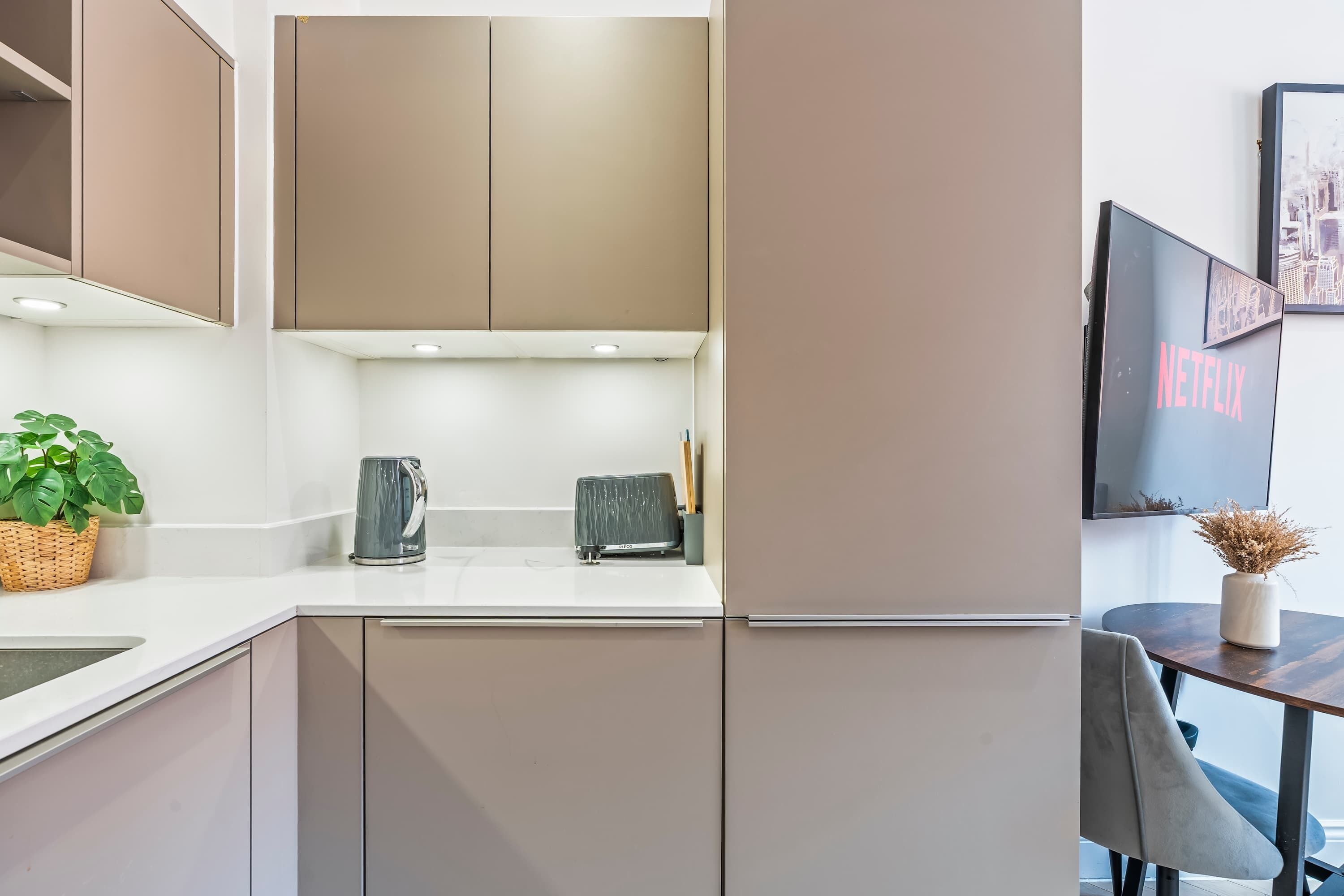 A modern kitchen with built-in cabinets, a kettle, and a coffee maker on the counter.
