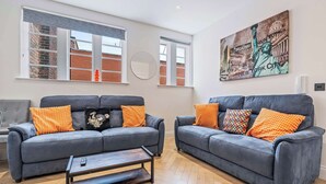 A living room with two grey sofas, a coffee table, and a large painting of the Statue of Liberty. - Modern Flat In Jewellery Quarter, Free Parking (Birmingham)