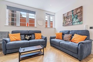 A living room with two grey sofas, a coffee table, and a large painting of the Statue of Liberty.