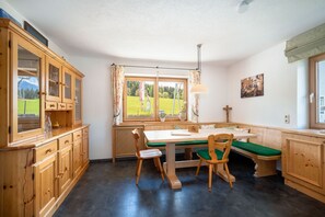 A wooden interior with a dining table, chairs, and a window with a view of a green landscape. - Grand Chalet Hochfilzen (Hochfilzen)