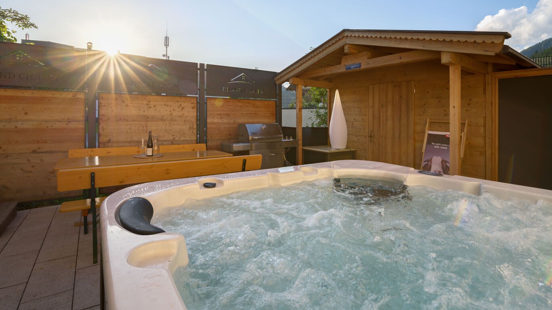 Ein Whirlpool mit Holzterrasse und Grill.