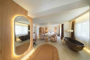 Una habitación de hotel moderna con un espejo grande, una bañera, un sofá, una mesita de café y una cama.