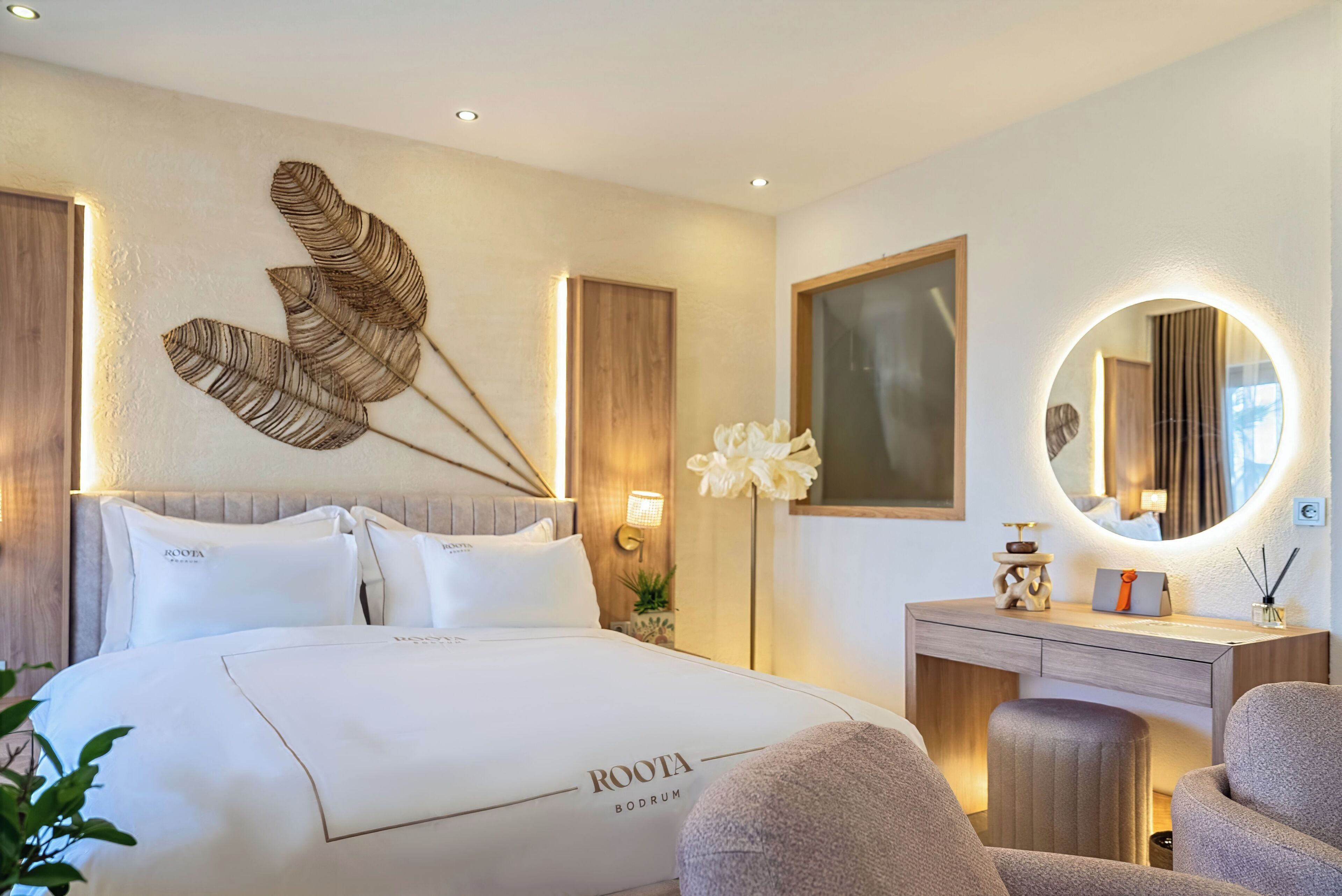 A hotel room with a bed, a bedside table, a mirror, and a wall-mounted artwork.