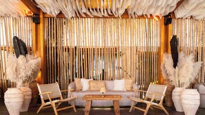 Una habitación con un sofá, dos sillones, una mesita de centro y una pared de bambú.