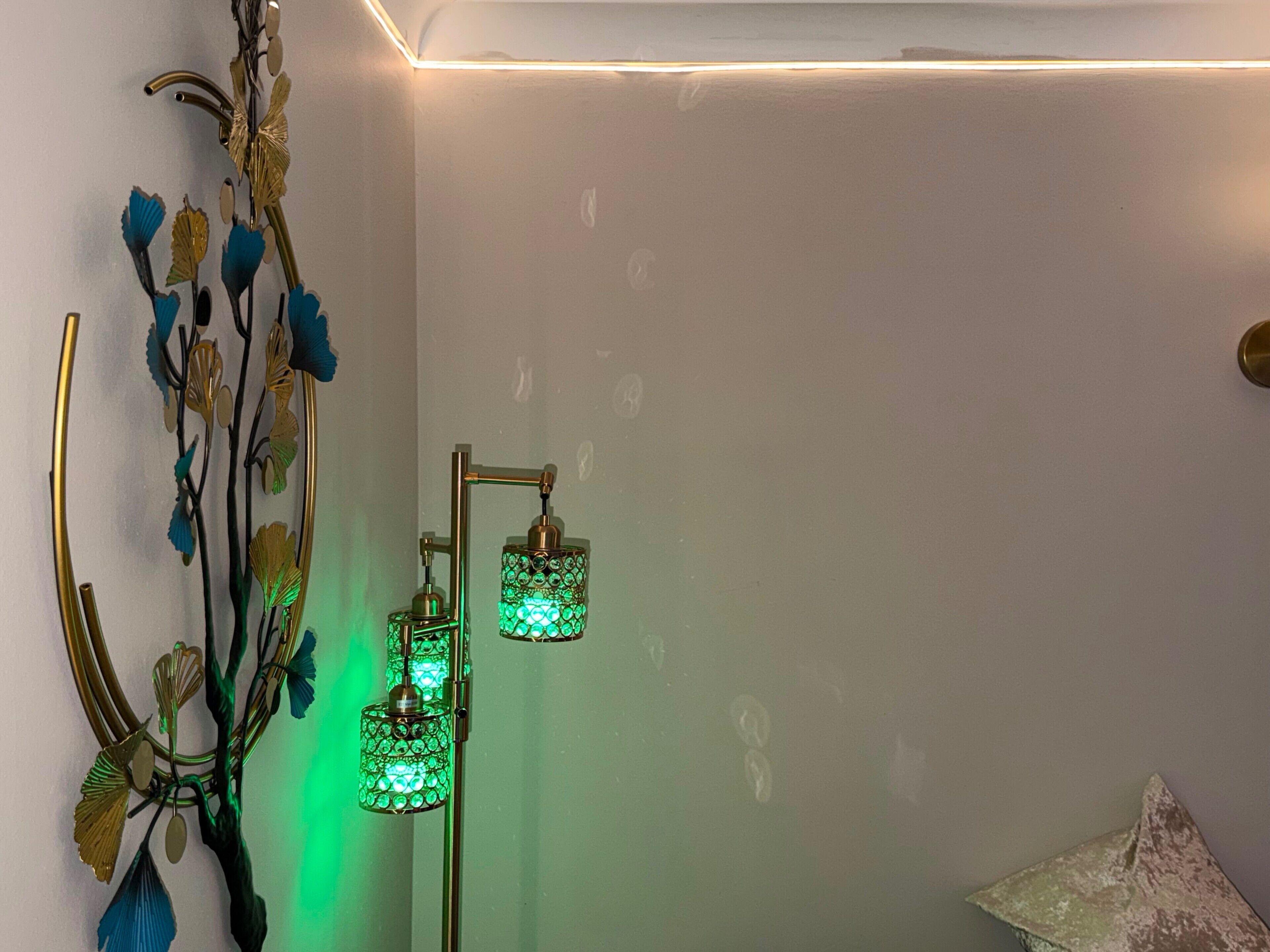 A room with a decorative wall piece and a floor lamp with green glass shades.