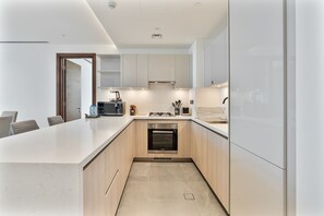 Una cocina moderna con una isla central, horno empotrado y armarios blancos.