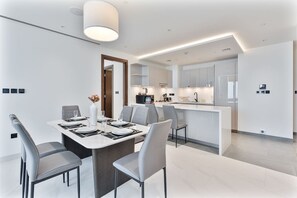 Una cocina moderna con una isla central, un comedor con mesa para cuatro y un diseño minimalista.