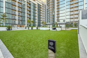 Een modern appartementencomplex met meerdere balkons, een verzorgd gazon en een bordje met de naam van het pand.