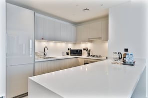 A modern kitchen with white cabinetry, a stainless steel sink, a microwave, and a coffee maker. - 2BR Apartment With iconic view+Ample of amenities (Dubai)