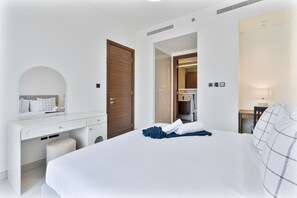 A hotel room with a bed, a desk, a mirror, and a wardrobe. - 2BR Apartment With iconic view+Ample of amenities (Dubai)