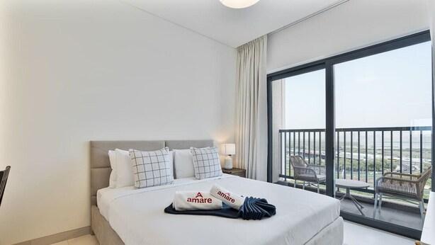 Ein Hotelzimmer mit einem großen Bett, einem Balkon mit Aussicht und einem ordentlich bezogenen Bett mit Handtuch.