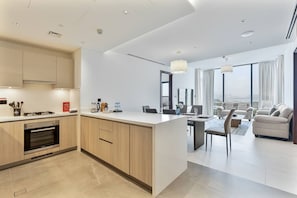 Une cuisine moderne avec un îlot central, un coin repas et un salon doté d’un canapé et offrant une vue sur la ville.