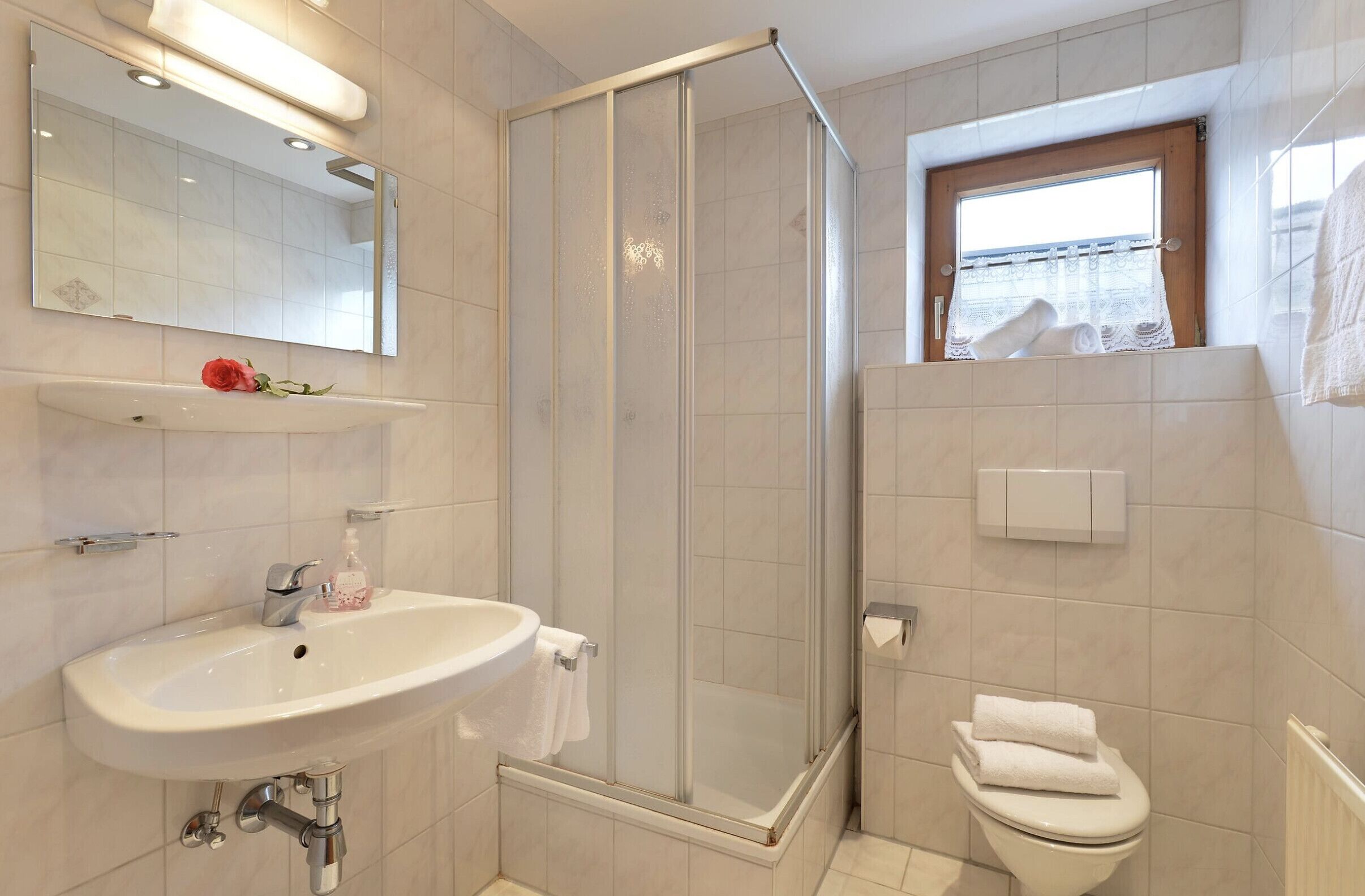 Ein modernes Badezimmer mit einer gläsernen Duschkabine, einem weißen Waschbecken und einer Toilette.