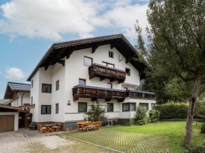 A two-story building with a balcony, a wooden deck, and a well-maintained lawn. - Haus Adler 3 by Alpine Host Helpers (Westendorf)
