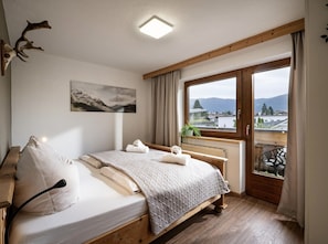 Ein Schlafzimmer mit einem Bett, einem Fenster mit Ausblick, einem Bild an der Wand und einer Deckenleuchte.
