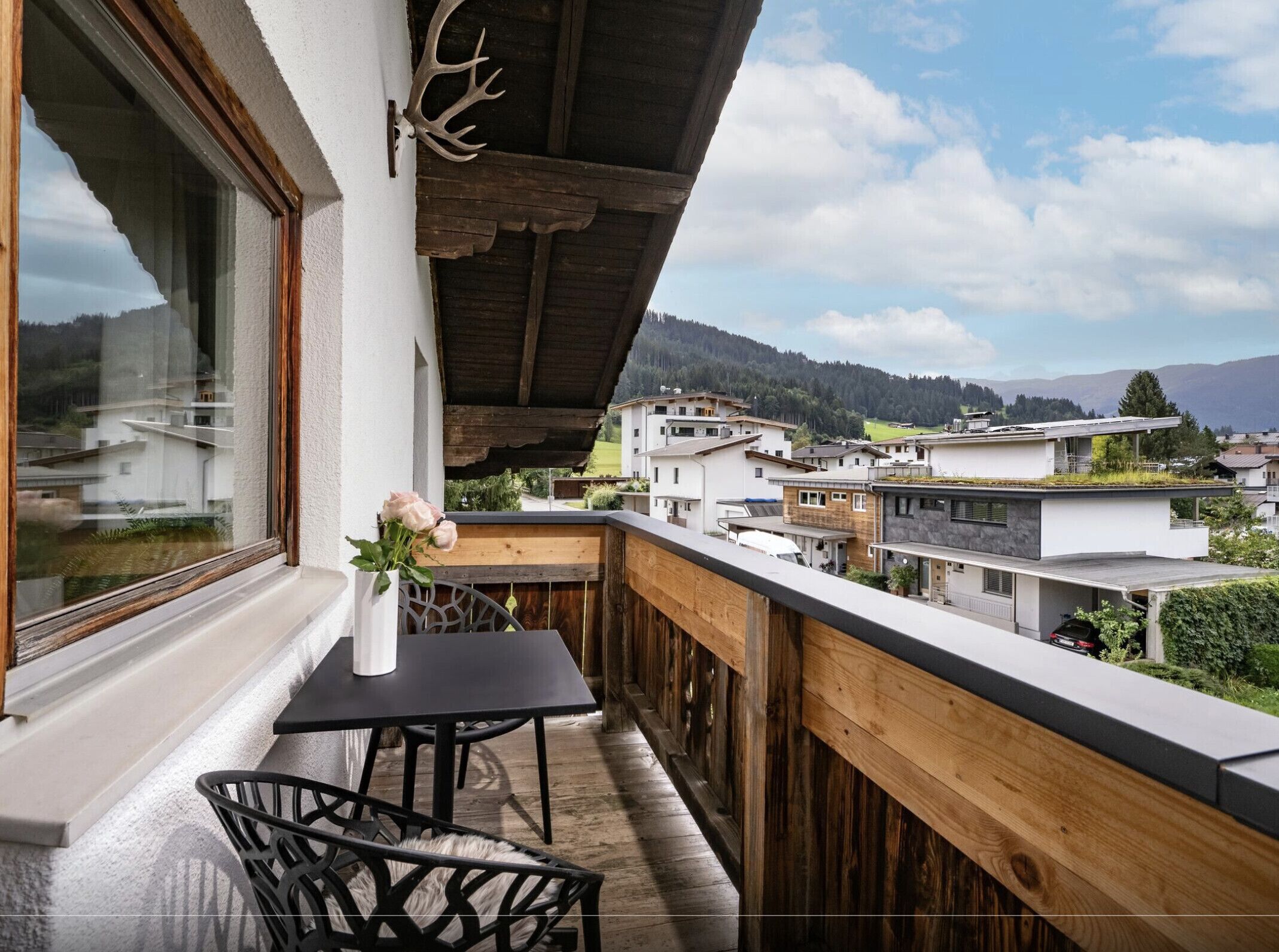 Een balkon met houten hekwerk, een tafel en een stoel.