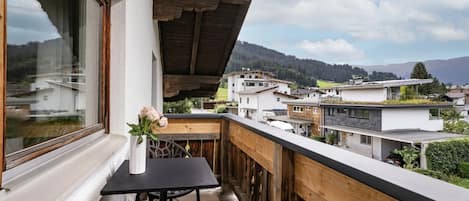 A balcony with a wooden railing, a table, and a chair.