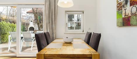 A dining area with a wooden table, chairs, a white bowl, and a pendant light.