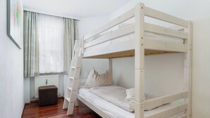 A bunk bed in a room with a window, a radiator, a wooden floor, and a ladder. - Kitz-Heart Standard Top 1 (Kitzbühel)