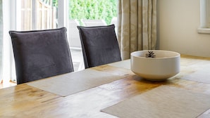 A dining table with a white bowl and two chairs, a hanging light fixture, and a view of greenery through a window. - Kitz-Heart Standard Top 1 (Kitzbühel)