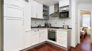 A modern kitchen with white cabinetry, a built-in oven, and a microwave. - Kitz-Heart Standard Top 1 (Kitzbühel)
