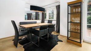 A modern dining area with a wooden table and black chairs, a black pendant light, and a glass wine cabinet. - Kitz-Heart Premium Top 2 (Kitzbühel)