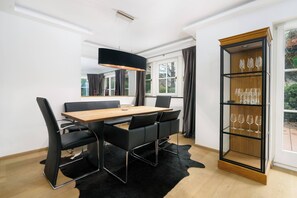 Ein moderner Essbereich mit einem Holztisch, schwarzen Stühlen, einer schwarzen Pendelleuchte und einer Weinklimaanlage.