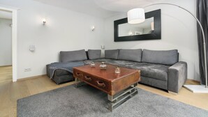A modern living room with a grey sofa, a wooden coffee table, and a large mirror on the wall. - Kitz-Heart Premium Top 2 (Kitzbühel)
