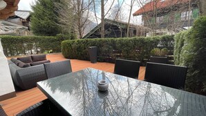 An outdoor patio area with a glass-top table, wicker furniture, and a potted plant. - Kitz-Heart Premium Top 2 (Kitzbühel)