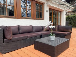 A sectional sofa with cushions, a square woven coffee table, and a potted orchid. - Kitz-Heart Premium Top 2 (Kitzbühel)