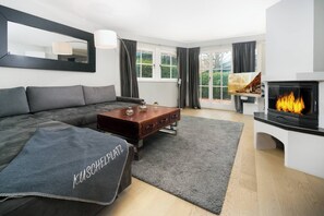 A modern living room with a sofa, coffee table, and fireplace.