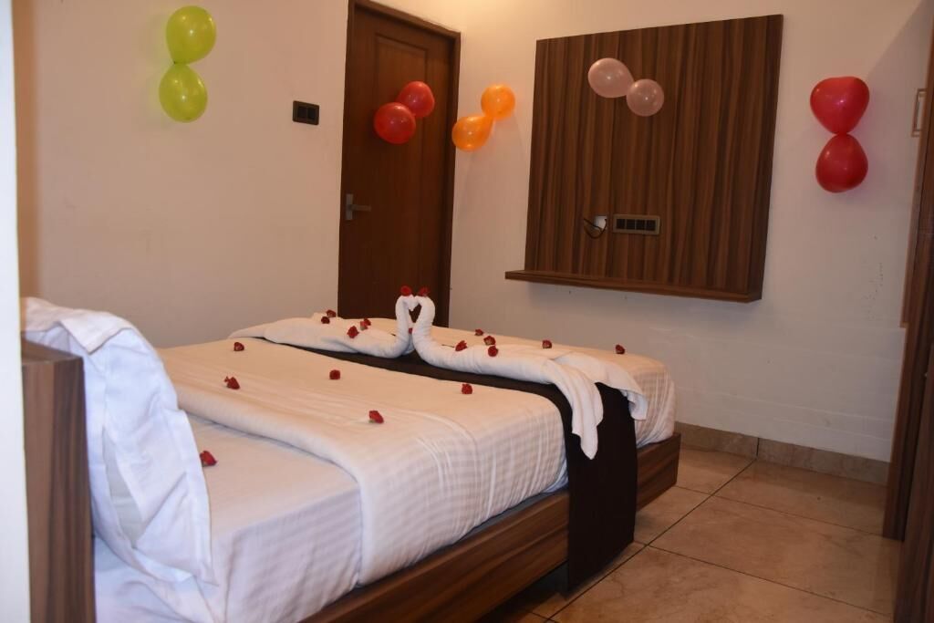 A hotel room with a bed, a wooden headboard, and a wall-mounted wooden panel.