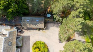 Un patio con suelo empedrado, un pequeño jardín y un edificio de techos inclinados.