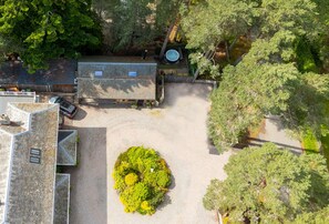 A courtyard with a paved area, a small garden, and a building with a sloped roof. - Wildcat Lodge - couples retreat for two with a hot tub (Boat of Garten)